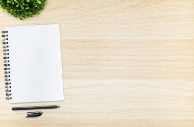 Ahşap masanın üstünde kalem olan defter. Kopyalama alanı olan üst görünüm, düz yatay.