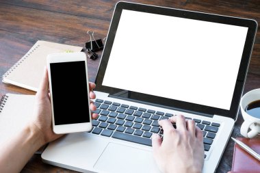 Mand akıllı telefon tutuyor ve dizüstü bilgisayarın klavyesine yazıyor. Uygulamaları montajlamak için boş ekranlar.