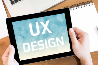 Bir adam ekranında UX DESIGN metinleri olan bir tablet tutuyor..