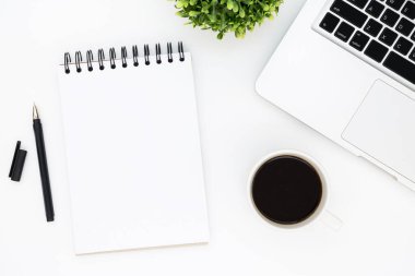 Beyaz ofis masası, boş defter sayfası, kalem, dizüstü bilgisayar ve kahve. Kopyalama alanı olan üst görünüm, düz yatay.
