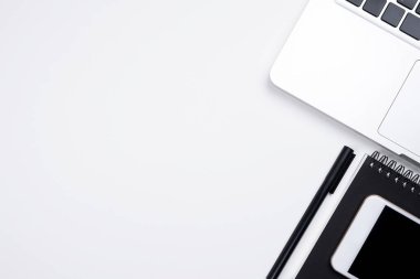 Laptop ve malzemelerle dolu beyaz ofis masası. Kopyalama alanı olan üst görünüm, düz yatay.