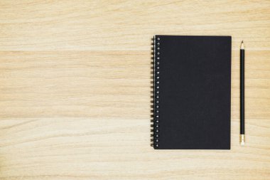 Kalemli siyah defter ahşap masanın üzerinde. Kopyalama alanı olan üst görünüm, düz yatay.