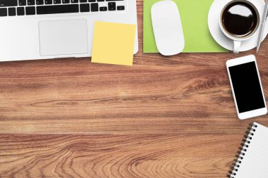 Laptop ve malzemelerle dolu ahşap ofis masası. Kopyalama alanı olan üst görünüm, düz yatay.