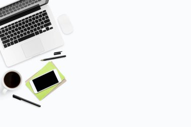 Laptop ve malzemelerle dolu beyaz ofis masası. Kopyalama alanı olan üst görünüm, düz yatay.