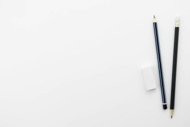 Kalemler ve silgi beyaz masanın üstünde. Kopyalama alanı olan üst görünüm, düz yatay.