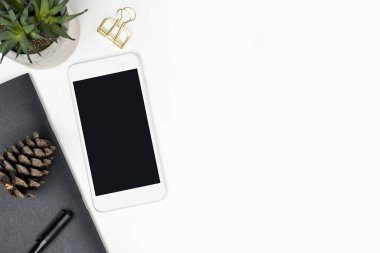 Akıllı telefon ve malzemelerle dolu beyaz masa. Kopyalama alanı olan üst görünüm, düz yatay.