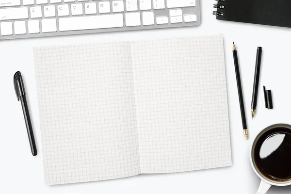 Blank grid lines notebook page on white desk. Top view, flat lay.