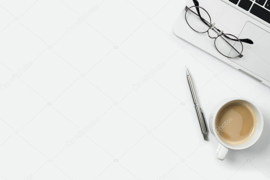 White office desk table with laptop, cup of coffee and supplies. Top view with copy space, flat lay.