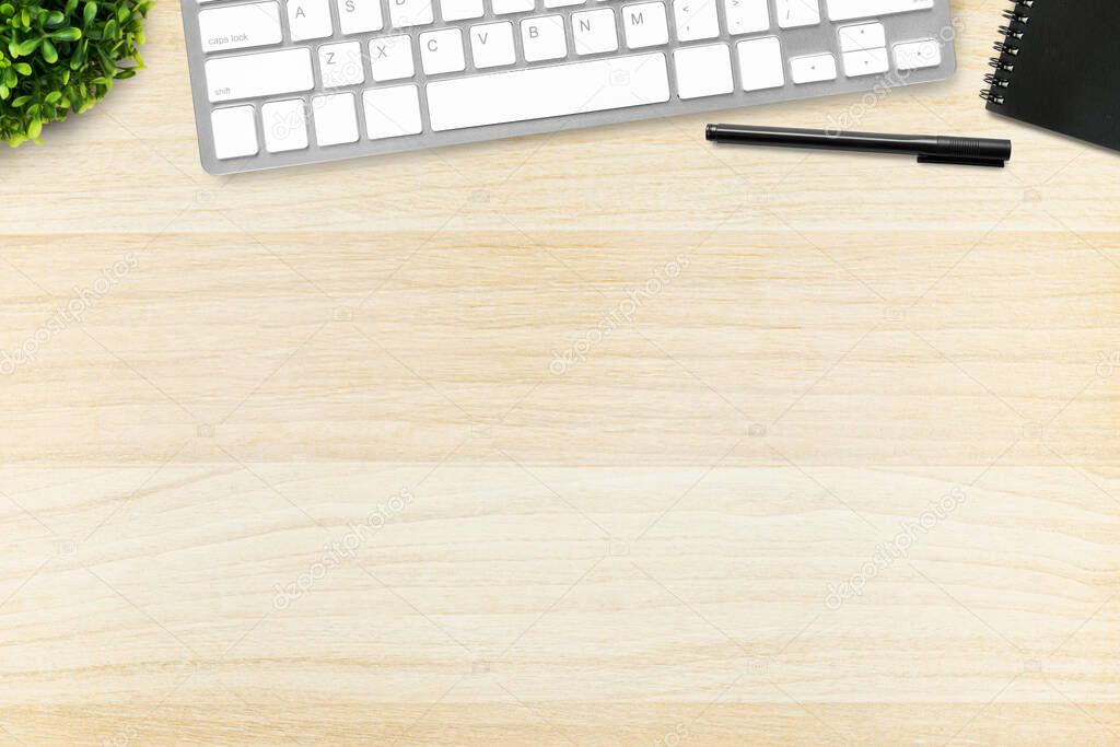 Wood office desk table with computer keyboard, pen and notebook. Top view with copy space, flat lay.