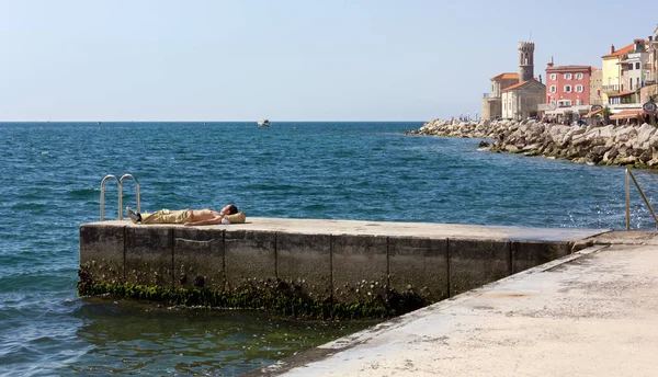 Junger Mann sonnt sich am Ufer des Piran — Stockfoto