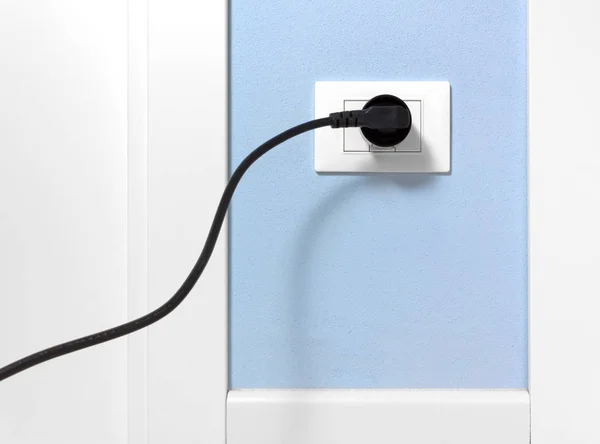 Plug preto em uma tomada de parede em uma parede azul — Fotografia de Stock