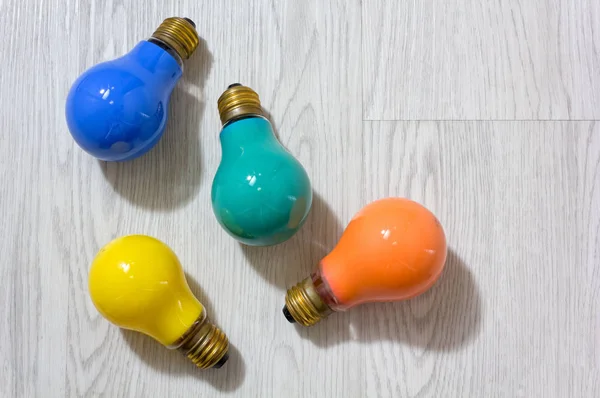 Quatro lâmpadas coloridas em um fundo de madeira — Fotografia de Stock