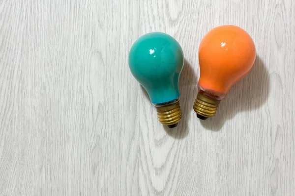 Twee gekleurde gloeilampen op een houten achtergrond — Stockfoto