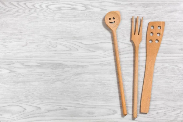 Cucchiaio di legno sorridente e altri due utensili su un Ba di legno bianco — Foto Stock