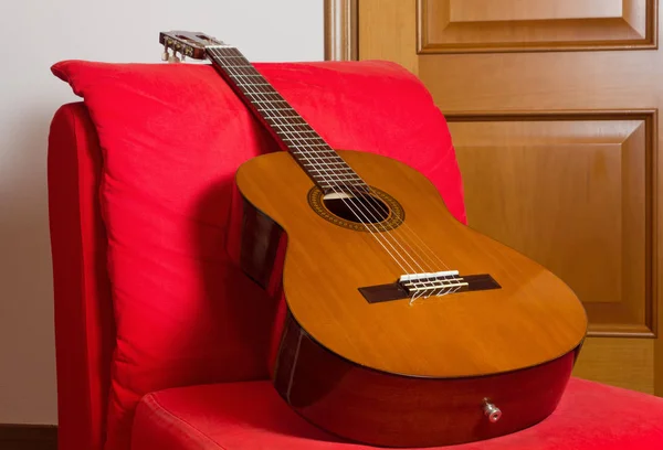 Guitarra clássica em uma cadeira vermelha fácil — Fotografia de Stock