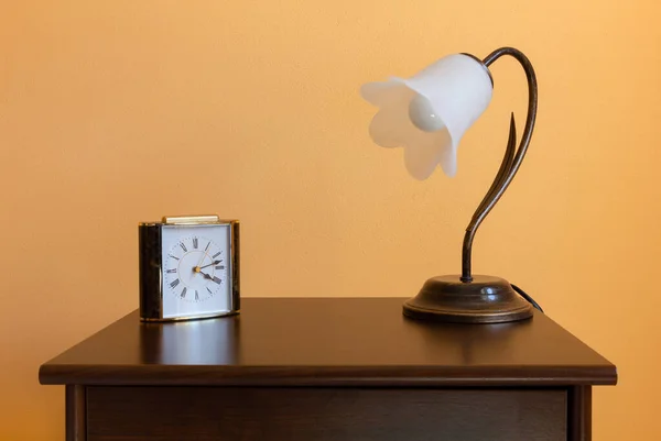 木制床头柜上的一盏经典花形灯和一个闹钟 — 图库照片