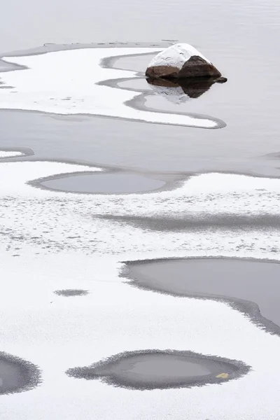 Río comienza a congelarse, roca asomándose fuera de las aguas poco profundas —  Fotos de Stock