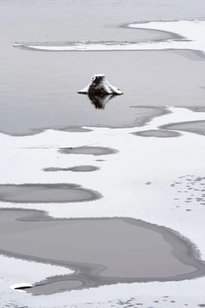 Río comienza a congelarse, viejo tocón asomándose fuera de las aguas poco profundas —  Fotos de Stock