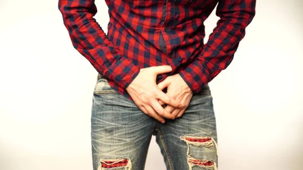 A young, attractive man feels pain in his groin, arms folded between his legs. — Stock Image Young Attractive Man Feels Pain His Groin Arms Folded His Royalty Free Stock Photos