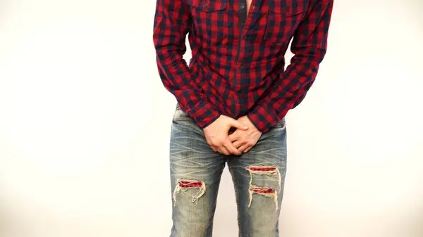 A young, attractive man feels pain in his groin, arms folded between his legs. — Stock Image Young Attractive Man Feels Pain His Groin Arms Folded His Stock Photo