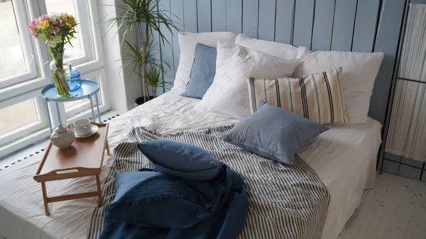 Wooden stand for breakfast on crumpled bed in studio. Close-up of interior design room.