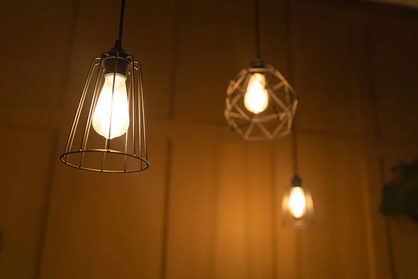 From below of modern lamps with geometric decoration in trendy loft dark room