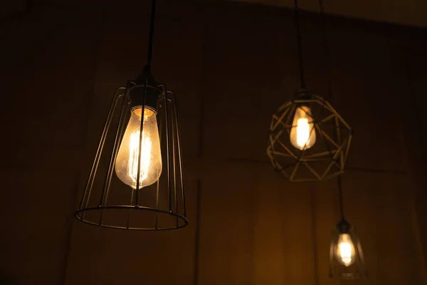 From below of modern lamps with geometric decoration in trendy loft dark room