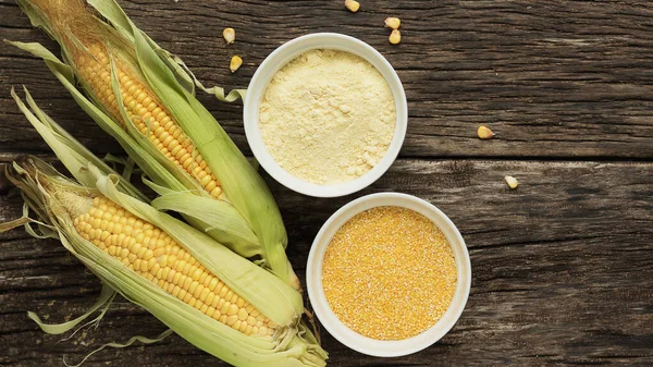 Polenta corn grits and corn flour in a porcelain bowl on a wooden table. Ears of corn and pieces of corn next to bowls. Gluten Free Healthy Eating — Stock Photo, Image