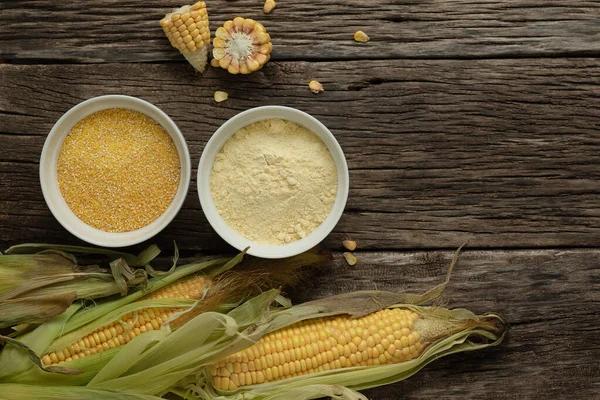 Polenta corn grits and corn flour in a porcelain bowl on a wooden table. Ears of corn and pieces of corn next to bowls. Gluten Free Healthy Eating