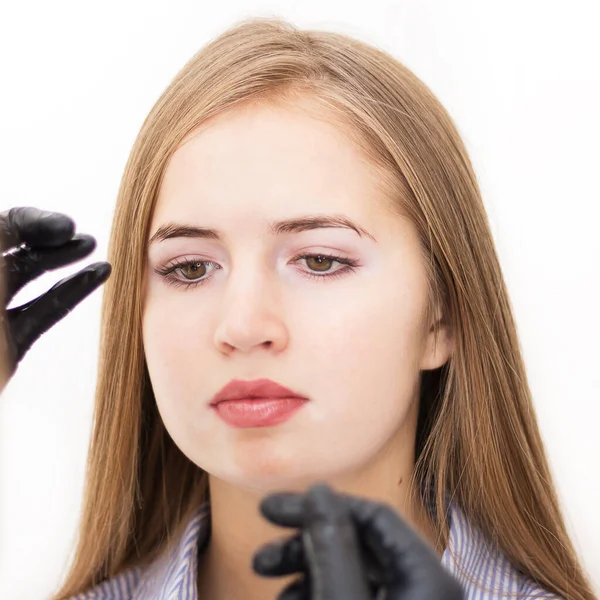 Female cosmetologist performs eyebrow correction on beautiful models in the beauty parlor. Fair-haired girl. Close-up. Facial care — ストック写真