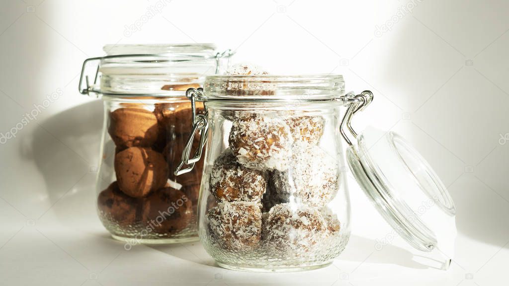 Energy balls in a jar with a yoke lock. Two containers with different dishes. Sharp shadows in daylight. Horizontal location