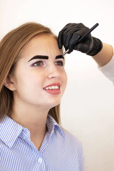 Female cosmetologist performs eyebrow correction on beautiful models in the beauty parlor. Fair-haired girl. Close-up. Facial care. Vitiligo pigmentation model. Safe eyebrow tinting with henna. Salon — Stock Photo, Image