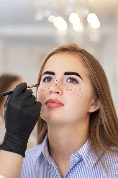 Un cosmetolog feminin efectuează corecția sprâncenelor pe un model frumos într-un salon de înfrumusețare. Aplicarea pistrui pe față, îngrijire a pielii și tratamente salon. Model cu pigmentare vitiligo. Tinting sigur — Fotografie, imagine de stoc