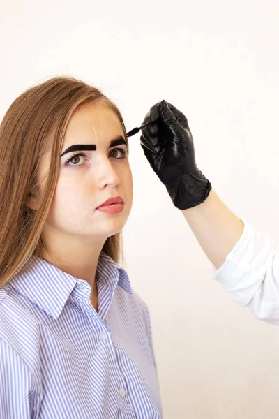 A female cosmetologist performs eyebrow correction on a beautiful model in a beauty salon. Girl with brown hair close-up. Facial and salon treatments. Model with vitiligo pigmentation. Safe tinting — Stock Photo, Image