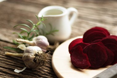 Pancar cipsi. Atıştırmalık yapma süreci. El yapımı sağlıklı sebze cipsi. Kesme tahtasının üzerinde kök sebze dilimleri var. Yemek için sarımsak ve kekik baharatı. Hazırlık için zeytinyağı kullanılıyor.