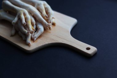 Çiğ tavuk bacakları kesme tahtasının üzerinde yatıyor. Keto, diyet ve sağlıklı bir diyet için sağlıklı organik bir ürün. Siyah arka plan. Yatay yönelim ve kopyalama alanı.