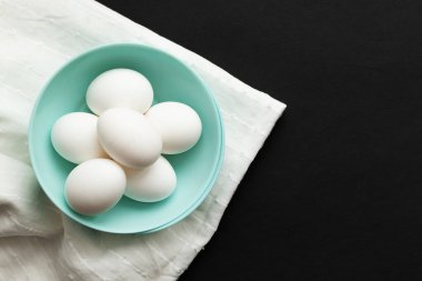 Geleneksel Paskalya yemeği yumurtaları. Beyaz peçete ve siyah arka planda renkli tabaklar. Minimalist tasarım. Renkler Trend 2020.
