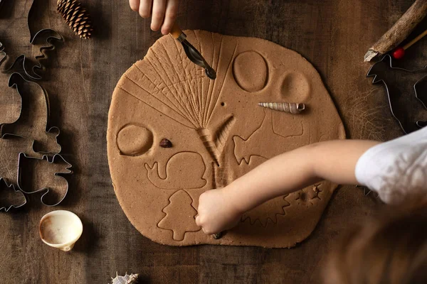 Children play with salt dough on the kitchen table. Hands mold clay with their own hands to create homemade zero-waist toys. Creative lesson with a test of natural products. Development of children in the period of self-isolation.