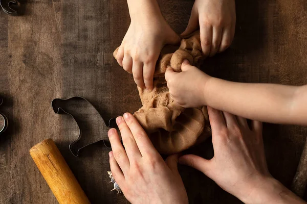 Children play with salt dough on the kitchen table. Hands mold clay with their own hands to create homemade zero-waist toys. Creative lesson with a test of natural products. Development of children in the period of self-isolation.