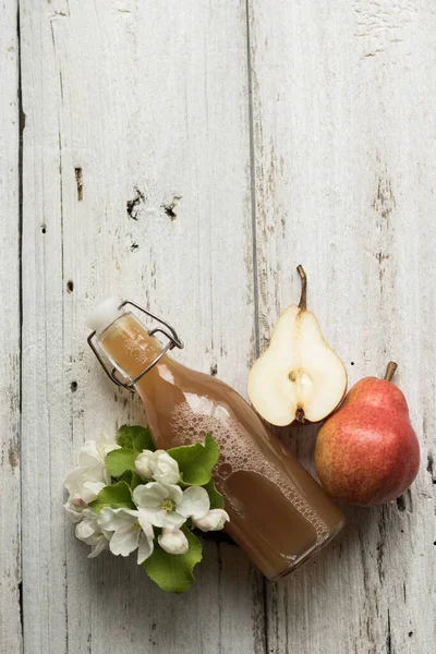 Bottle of apple and pear juice, fresh pears and flowers on a wooden background. Country style.