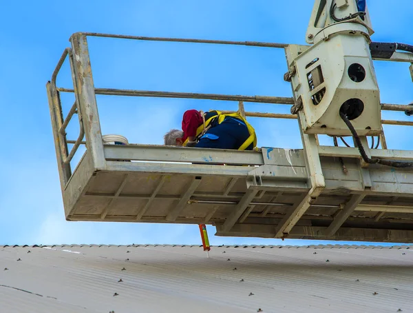 Trabajador repara la cubierta metálica en una pequeña cesta de pasajeros —  Fotos de Stock