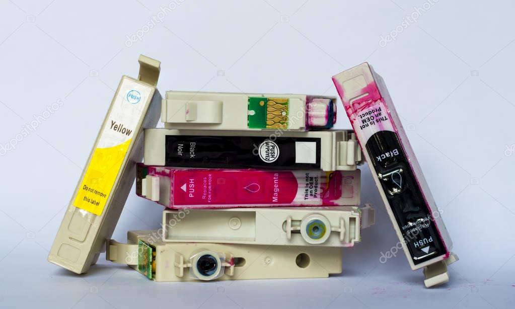 Empty ink cartridges with labels of various colors stacked on wh