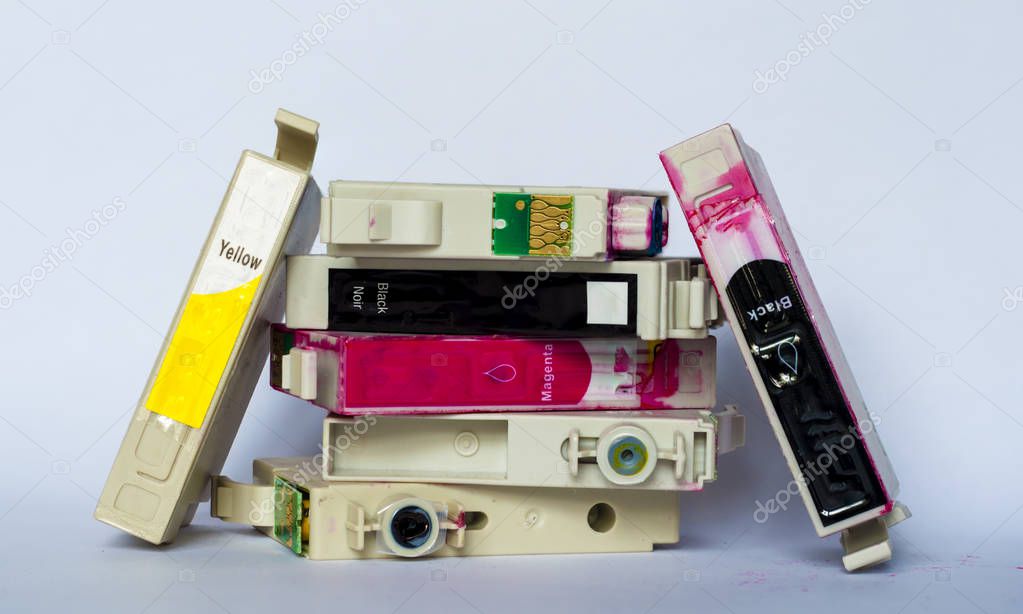 Empty ink cartridges with labels of various colors stacked on white background.