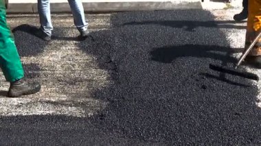 Asfalt kaldırım onarımı veya inşaat çalışmaları sırasında asfaltı düzleştiren işçiler