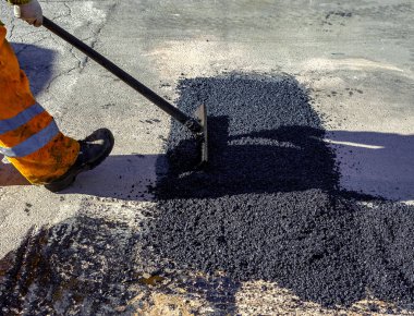 Asfalt kaldırım onarımı veya inşaat çalışmaları sırasında asfaltı düzleştiren işçiler