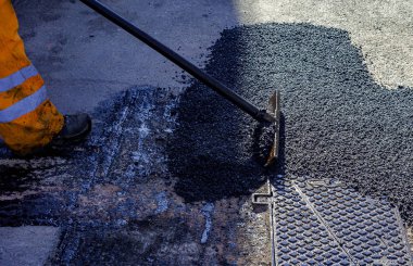 Asfalt kaldırım onarımı veya inşaat çalışmaları sırasında asfaltı düzleştiren işçiler