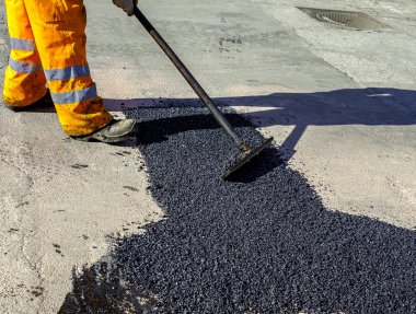 Asfalt kaldırım onarımı veya inşaat çalışmaları sırasında asfaltı düzleştiren işçiler