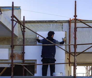 İnşaat alanında köpük levha yalıtım duvar yerleştirerek işçi