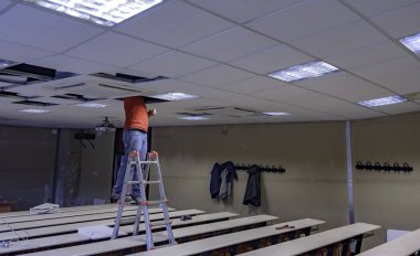 İşçi alçıtaşıyla tahta tavanı onarıyor. Sınıfta. 