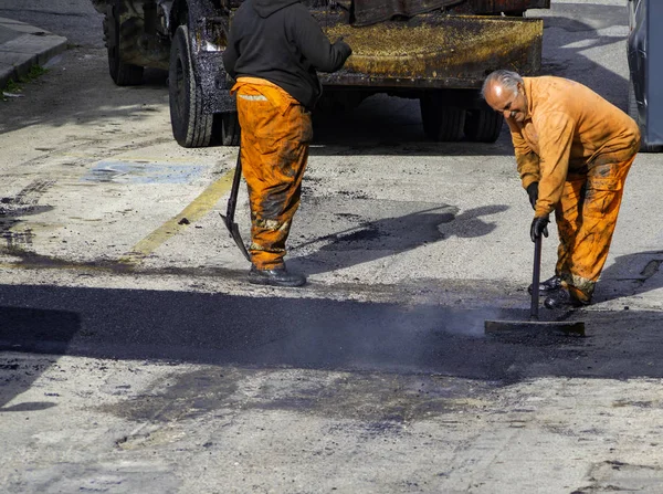 Arbetstagaren reglerar att lägga ny asfalt för att lappa en bula i vägen. — Stockfoto